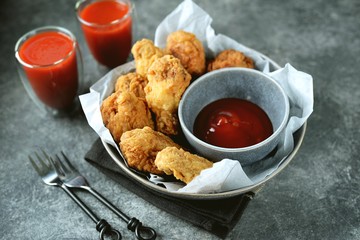 Delicious homemade deep fried breaded chicken wings with tomato sauce on a gray background. Unhealthy fast food.