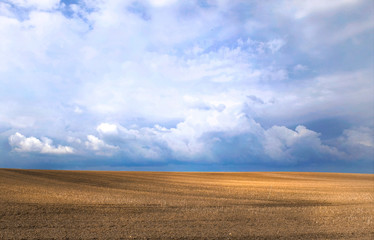A beautiful field under the blue sky with clouds. The field after the harvest, agricultural landscape
