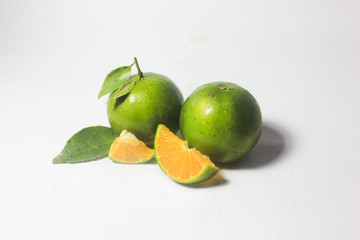 Group of fresh green citrus fruits and their leaves which have orange color inside and slice in different size and set in white color