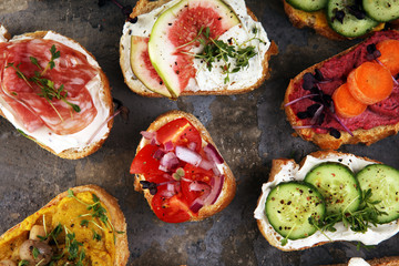 Assorted bruschetta with various toppings. Appetizing bruschetta or brie crostini. Variety of small sandwiches. Mix bruschetta on table