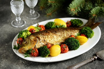 Baked carp fish with potatoes, cherry tomatoes and broccoli. Healthly food.