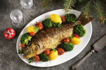 Baked carp fish with potatoes, cherry tomatoes and broccoli. Healthly food.