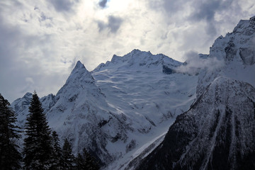 Snowy Mountains peaks in the clouds blue sky Caucasus