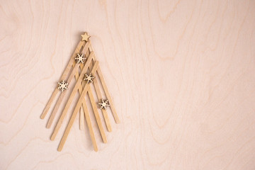 Christmas tree made of a wooden mixer sticks on a wooden background top view. Eco New year card design. Zero waste