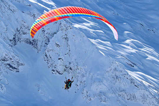 paraplane flying over snowy Caucasus mountains sunny blue sky