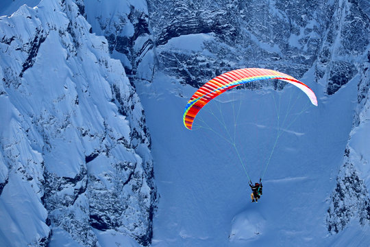 paraplane flying over snowy Caucasus mountains sunny blue sky