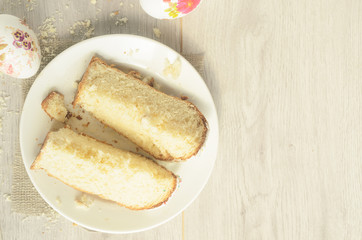 Holiday of Easter.Top view, slices of sweet Easter cake on a plate and Easter eggs on a light wooden background,copyspace.
