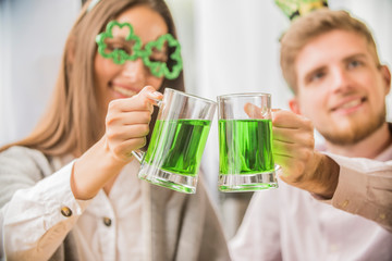 The company of young people celebrate St. Patrick's Day. They have fun at the bar. They are dressed...