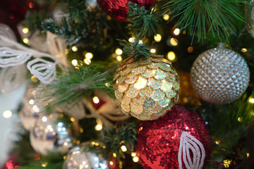 Christmas decorations on xmas tree with hanging balls and ornaments and bokeh background.