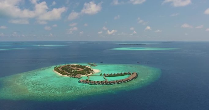 Maldivian resort aeral view taken by drone of tropical island with clear blue transparent turquoise ocean water. Blue cloudy sunny sky. Concept of sea coast  summer tropical vacation. 