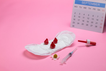 Obraz na płótnie Canvas menstruation calendar with Sanitary pad and sanitary napkin, bloods, calendar and injection close-up on a pink background.