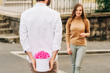 Man offering flower box of pink roses to beautiful young woman