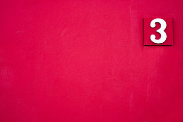 Elegant white number 3, three, offset on burgundy red backgrouund.