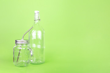 Reusable glass bottle and jar with metal straw on the light green drop, zero waste concept