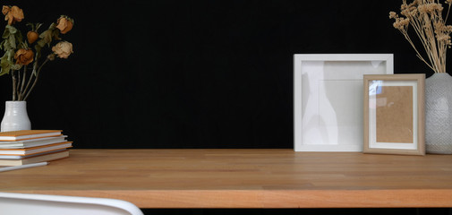 Close-up view of contemporary workplace with office supplies and copy space on wooden table and black wall