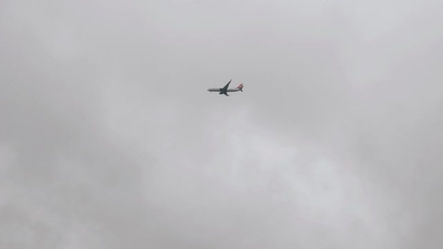 Passenger airliner flies in the clouds low above the ground. Cloudy weather.