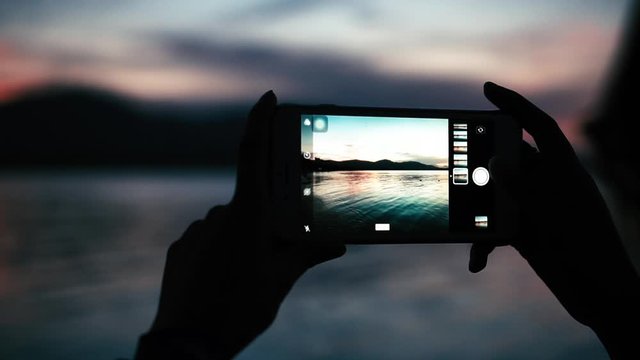 woman tke a photo on the beach,take sunrise photo