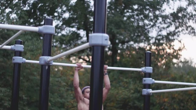 dolly shot of a young ripped man doing muscle ups in an outdoor calisthenics sports park