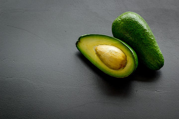 Avocado - ripe and bright, cutted in half - on black background closeup copy space