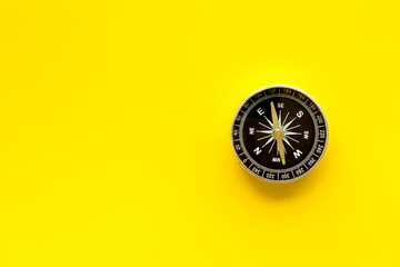 Compass - small and stylish - on yellow background top view copy space