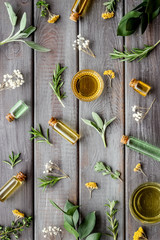 Fototapeta na wymiar Essential oils and fresh herbs on dark wooden background top view pattern