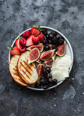Snack appetizers tapas plate with cheese, figs, olives, berries on a dark background, top view © okkijan2010