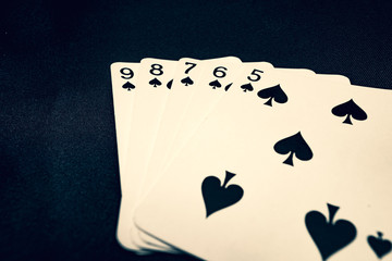 Straight flush of spades on black background