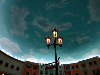 lampposts enlightening the pavement and silhouettes of bystanders