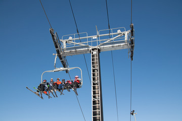 skiers and snowboarders are sitting on a ski cable chair lift