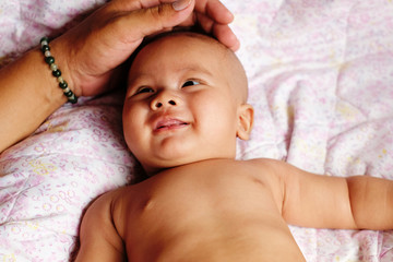 Portrait of a cute 2 months Asian baby on the bed.