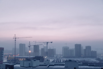 Fototapeta na wymiar Panorama of construction at sunset. Construction of a residential complex with cranes.