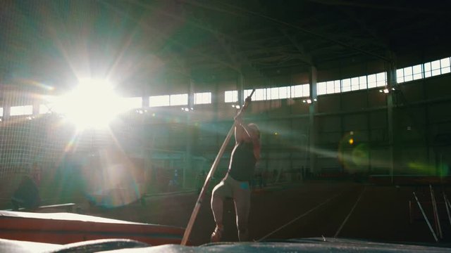 pole vaulting - young woman is running and jumping over the bar