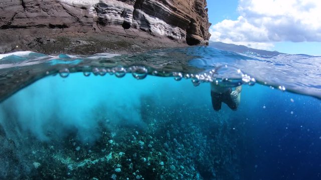 Man Swimming In Rough Tropical Sea Beside Coral Cliff