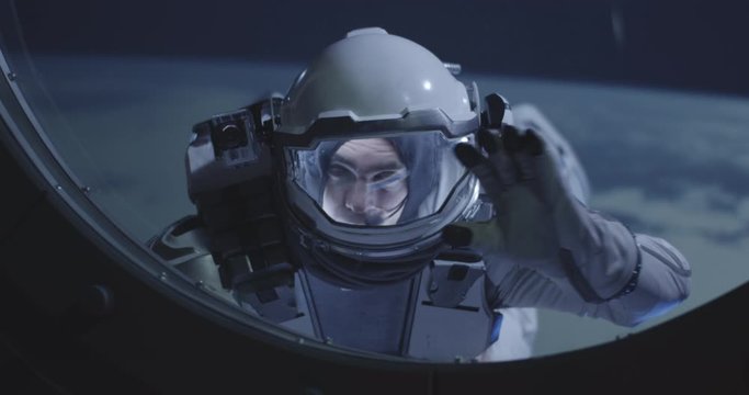 Astronaut floating by spacecrafts window