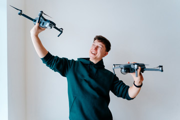 Fototapeta na wymiar Guy holds two quadrocopters against a wall