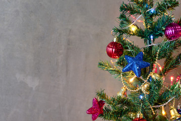 A beautiful Christmas tree adorned with glittering lights placed in front of  the concrete wall.