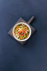 Olive salad for muffuletta in a bowl on a dark wooden board.