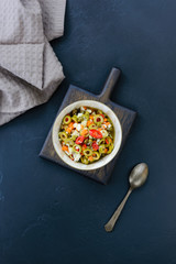 Olive salad for muffuletta in a bowl on a dark wooden board.