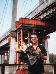 Obraz na płótnie Canvas Guy reads a burning newspaper, in the background a bridge