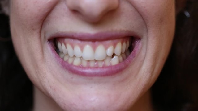 Close up of female mouth that grinds the teeth and passes the tongue between the teeth