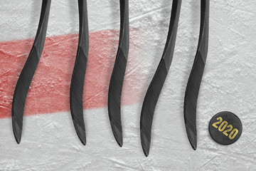 Five hockey sticks and puck on ice with a red line