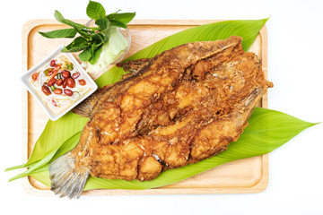 Deep fried sea bass with fish sauce and green mango chili fish sauce, based on chili fish sauce, addition of shredded green mango and lime juice serving on wooden tray isolated on white background.