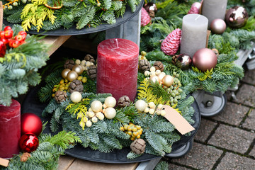 Traditional advent wreaths with single big dark red candle and seasonal Christmas decorations on...