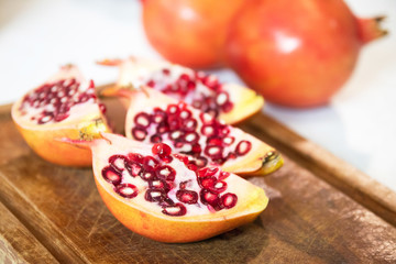 Pomegranate (Punica granatum) slice on wooden cutting board. 