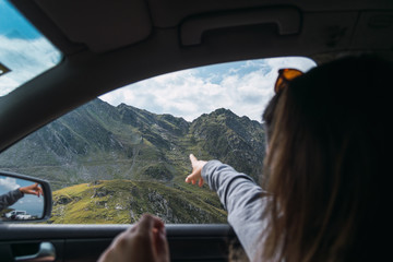 Resting anonymous lady showing on mountains from car