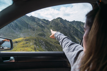 Female traveler pointing to green mountain from car