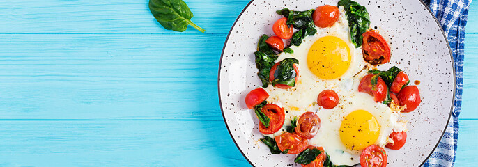 Plate with a keto diet food. Fried egg, spinach, and tomatoes. Keto, paleo breakfast. Top view, banner