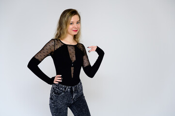 Concept of a woman talking to the camera. A photo of a pretty smiling girl with long beautiful curly hair in a black T-shirt on a white background is standing right in front of the camera.