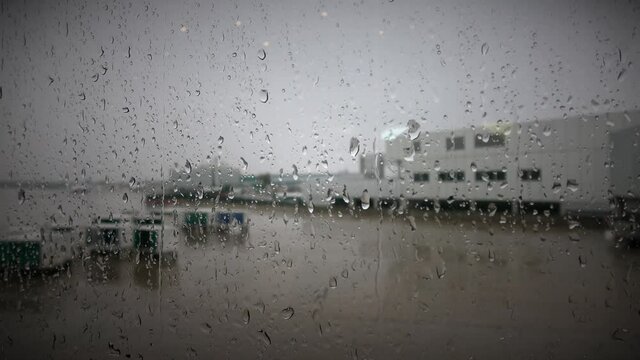 4K. Close up of raindrops wetting the glass of Cleveland Airport. View of Cleveland Airport on a rainy winter day. Cleveland is a known city in the state of Ohio.