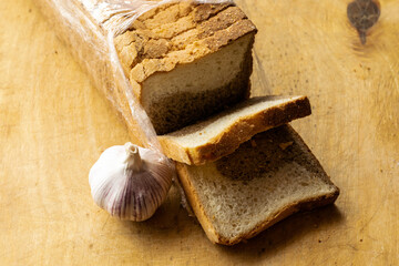 a loaf of sliced bread and a head of garlic lie on the cutting board